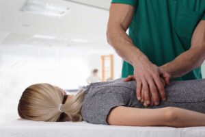 Person gently turning their neck while seated near a window, with a cervical spine illustration nearby.